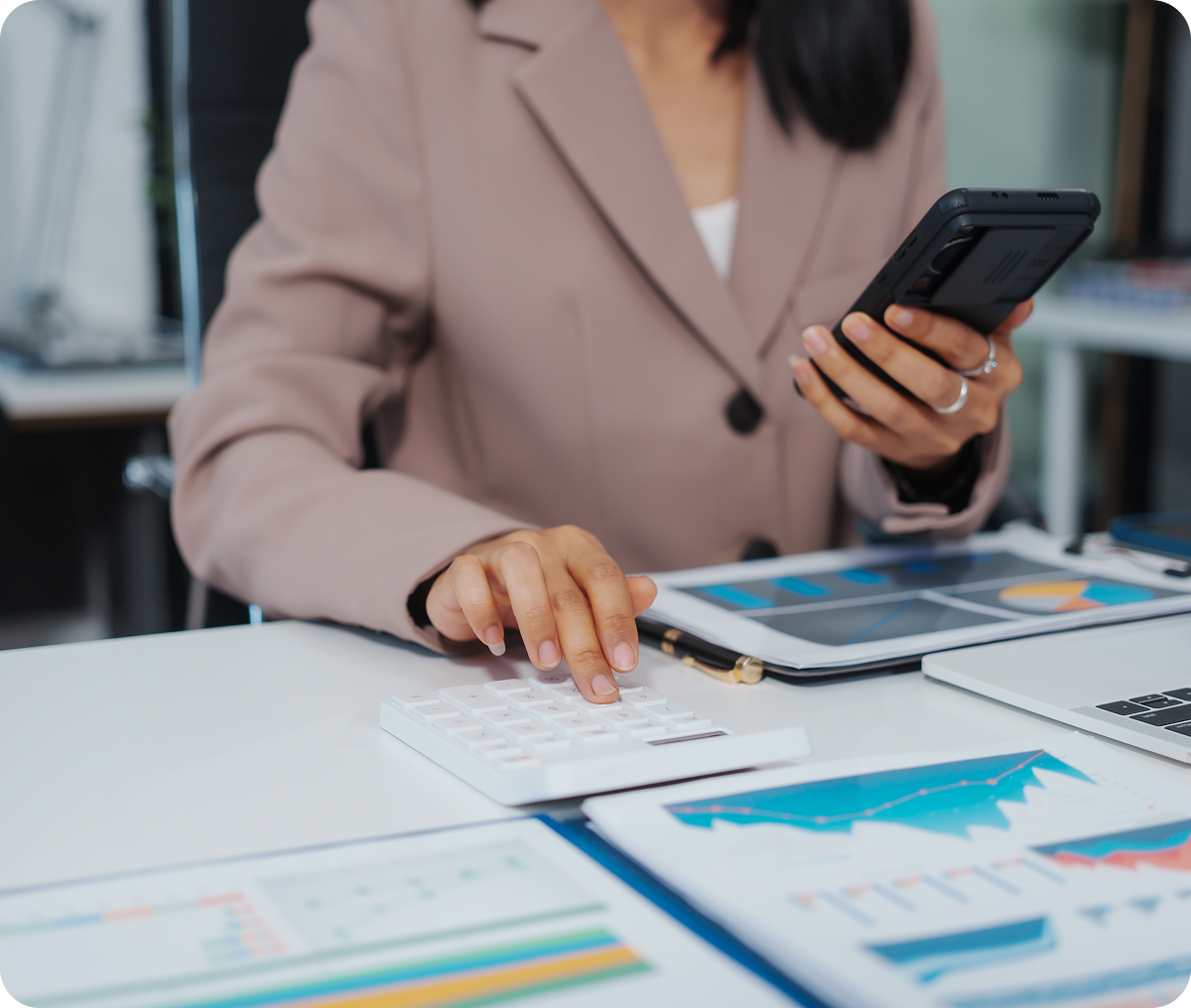 Businesswoman calculating with phone and documents.