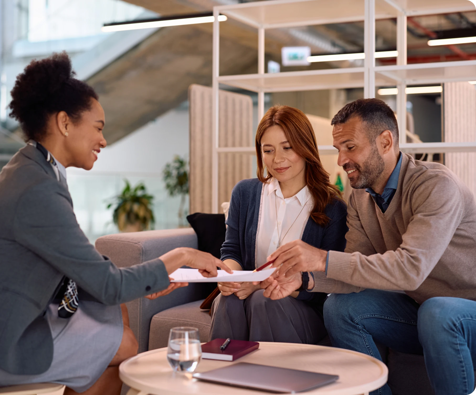 Three people discussing documents in office.