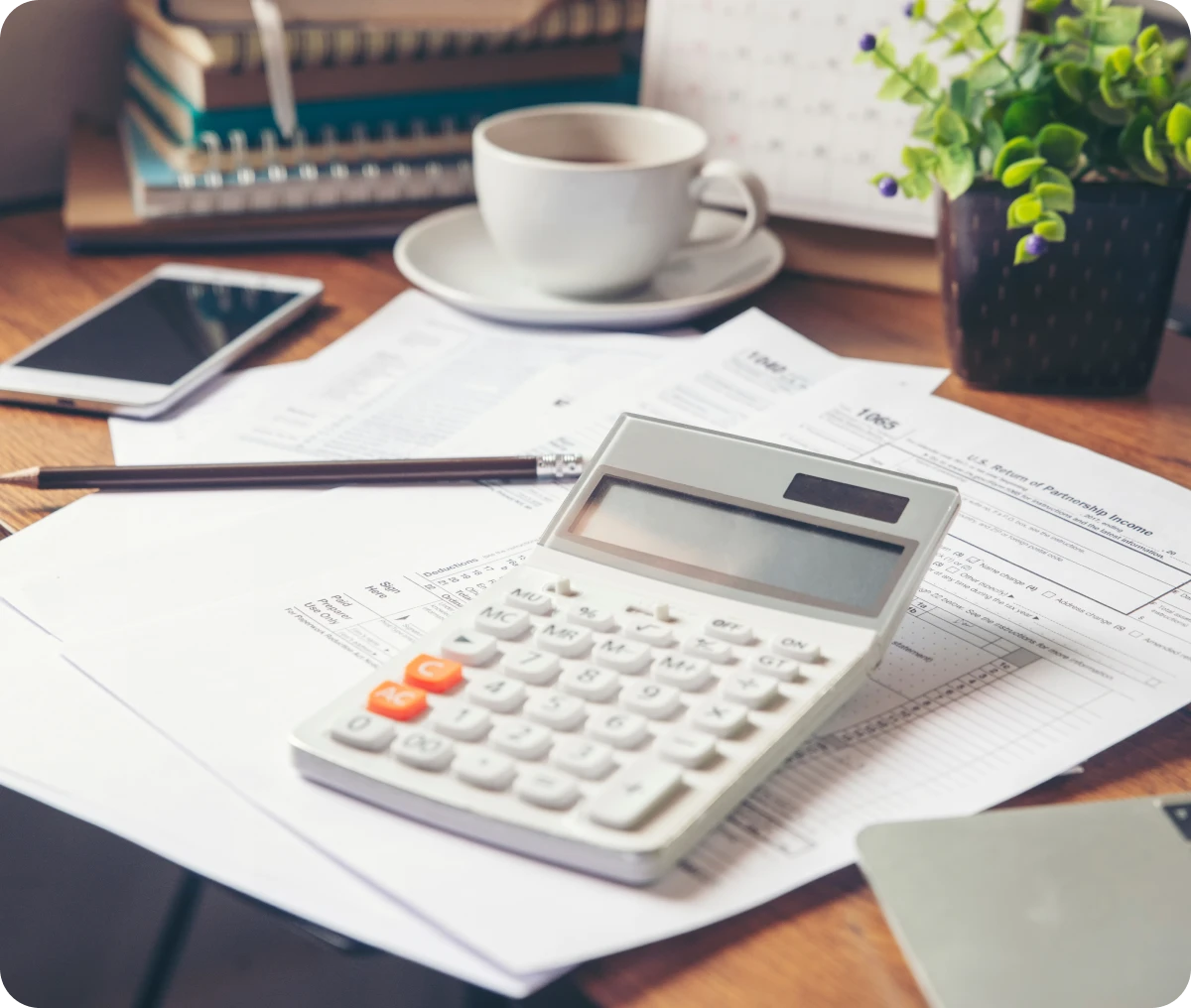 Calculator, documents, and coffee on a desk.
